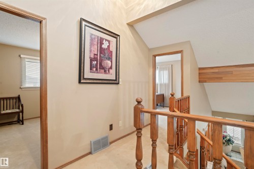 Upper-level landing featuring wood-finish railings, neutral-toned walls, and carpet flooring - 9831 158 Avenue, Edmonton, AB - Indoor Photo Showing Other Room