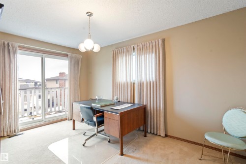 Room featuring a sliding glass door to a balcony with white railings, a three-light chandelier, a single window, and neutral wall paint - 9831 158 Avenue, Edmonton, AB - Indoor Photo Showing Office