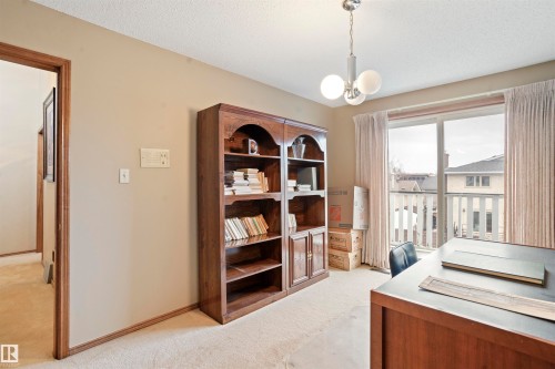 Room featuring plush carpeting, warm-toned walls, and a multi-globe pendant light fixture - 9831 158 Avenue, Edmonton, AB - Indoor