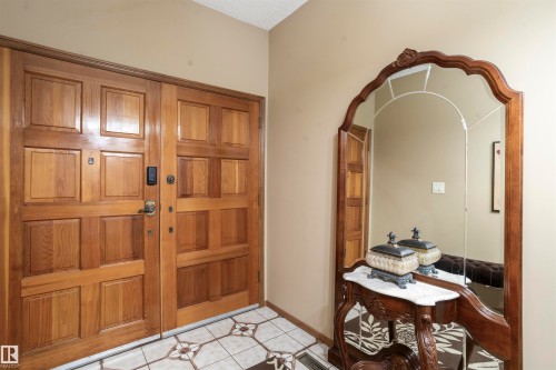 Double wood-paneled entry doors with smart lock hardware - 9831 158 Avenue, Edmonton, AB - Indoor Photo Showing Other Room