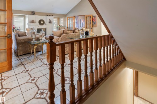 Wood staircase with carved balusters and a wood-finish handrail overlooking a living area - 9831 158 Avenue, Edmonton, AB - Indoor Photo Showing Other Room