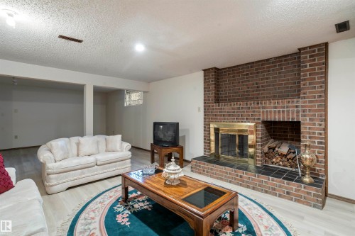 Brick fireplace featuring a brass firebox and tile hearth - 9831 158 Avenue, Edmonton, AB - Indoor Photo Showing Living Room With Fireplace