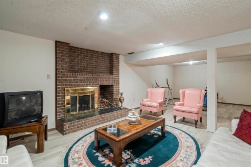 Brick fireplace with a brass-trimmed firebox and black stone hearth - 9831 158 Avenue, Edmonton, AB - Indoor Photo Showing Living Room With Fireplace