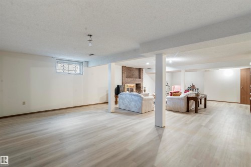 Spacious lower level featuring light wood-finish flooring, white walls, and exposed ceiling beams - 9831 158 Avenue, Edmonton, AB - Indoor
