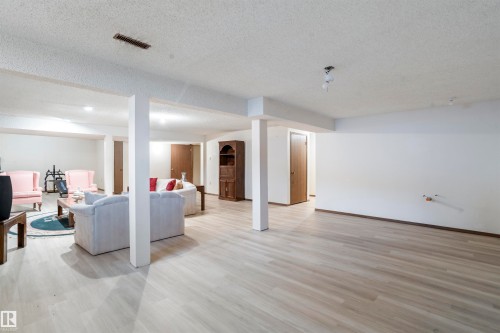 Spacious finished basement featuring light wood-finish flooring, recessed lighting, and support columns - 9831 158 Avenue, Edmonton, AB - Indoor