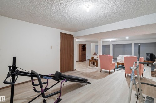 Finished basement featuring light wood-finish flooring, white painted walls, and an exposed beam ceiling - 9831 158 Avenue, Edmonton, AB - Indoor
