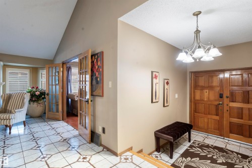 Entryway featuring a wood-panel front door, an ornate chandelier, and patterned tile flooring - 9831 158 Avenue, Edmonton, AB - Indoor Photo Showing Other Room