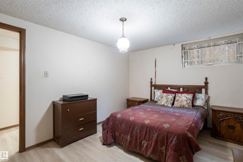 Room featuring wood-finish flooring, a textured ceiling, and a single window with decorative security bars - 9831 158 Avenue, Edmonton, AB - Indoor Photo Showing Bedroom