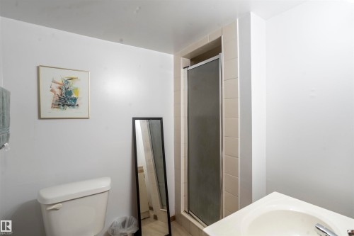 Bathroom featuring a white toilet, enclosed shower with frosted glass doors, and a vanity with an integrated sink - 9831 158 Avenue, Edmonton, AB - Indoor Photo Showing Bathroom