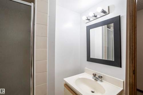 Bathroom featuring a vanity with an integrated sink, chrome faucet, and a wall-mounted mirror with a dark frame - 9831 158 Avenue, Edmonton, AB - Indoor Photo Showing Bathroom