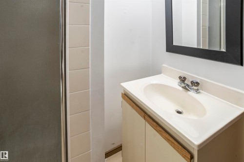 Bathroom vanity featuring an integrated sink, dual-handle faucet, and framed mirror - 9831 158 Avenue, Edmonton, AB - Indoor Photo Showing Bathroom