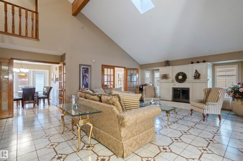 Spacious living room featuring vaulted ceilings with exposed wood beams, a skylight, and a fireplace with a decorative mantel - 9831 158 Avenue, Edmonton, AB - Indoor Photo Showing Living Room With Fireplace