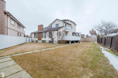 Expansive rear yard featuring an established lawn, concrete paver pathway, and a white chain-link fence - 9831 158 Avenue, Edmonton, AB - Outdoor