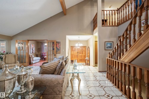 Vaulted ceiling with exposed wood beam, wood-finish staircase with turned balusters, patterned tile flooring, double wood entry doors, and French doors leading to an additional space - 9831 158 Avenue, Edmonton, AB - Indoor Photo Showing Other Room