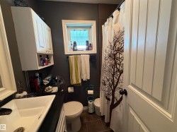 Bathroom featuring a white vanity with a rectangular sink, a white toilet, and a window providing natural light - 