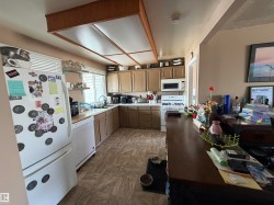 The kitchen features an L-shaped counter layout, light brown cabinetry, and a white refrigerator - 