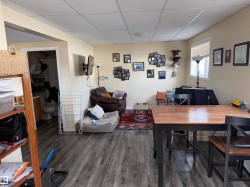 Open concept living area featuring wood-look flooring, a dining area with a wood table, and a window with blinds - 
