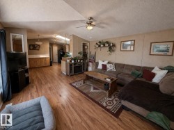 Spacious open concept living area featuring wood-look flooring, a ceiling fan, and a built-in media console with shelving - 