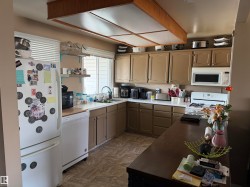 The kitchen features a white refrigerator, a dishwasher, and a microwave - 