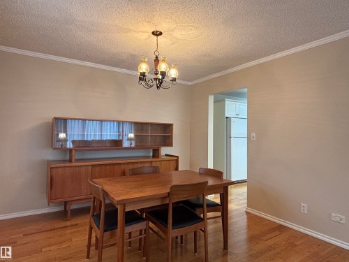 Dining area featuring wood-finish flooring, a decorative chandelier, and crown molding - 11139 30 Avenue, Edmonton, AB - Indoor Photo Showing Dining Room