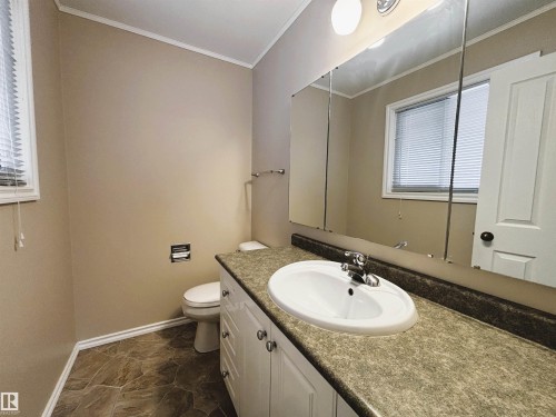 Bathroom featuring a single vanity with a white basin and chrome faucet, under-sink white cabinetry, and a full-width mirror - 11139 30 Avenue, Edmonton, AB - Indoor Photo Showing Bathroom