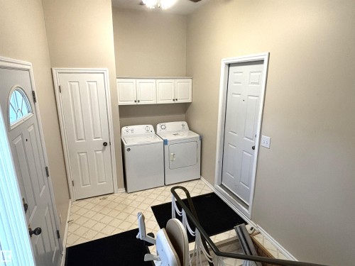 Laundry area featuring upper cabinetry, white appliances, patterned floor tile, and multiple paneled doors - 11139 30 Avenue, Edmonton, AB - Indoor Photo Showing Laundry Room