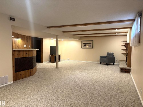 Expansive room featuring exposed wood ceiling beams, recessed lighting, and a built-in wood-paneled wet bar with a countertop - 11139 30 Avenue, Edmonton, AB - Indoor Photo Showing Basement