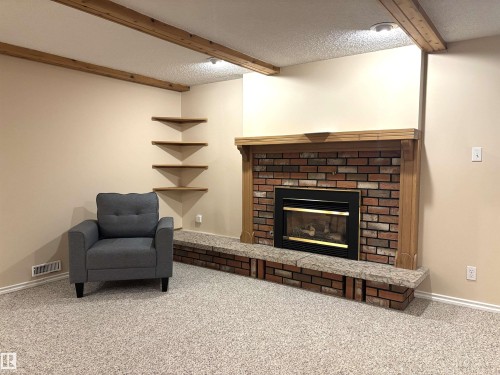 Brick fireplace with a black firebox and a light wood mantel - 11139 30 Avenue, Edmonton, AB - Indoor With Fireplace