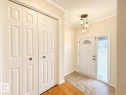 Entryway featuring a decorative ceiling light fixture, a paneled door with an arched window, a textured glass sidelight, and patterned flooring - 11139 30 Avenue, Edmonton, AB  - Indoor Photo Showing Other Room 