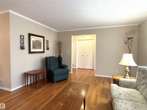 Spacious living area featuring warm wood-finish flooring, neutral wall tones, and white crown molding - 11139 30 Avenue, Edmonton, AB - Indoor Photo Showing Living Room