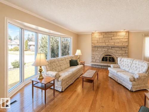 Living area featuring a stone-clad fireplace with an arched firebox, a stone hearth, and recessed lighting - 11139 30 Avenue, Edmonton, AB - Indoor Photo Showing Living Room With Fireplace