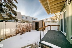 The property features a deck area with a wooden railing and an overhang, overlooking a fenced yard with a storage shed - 