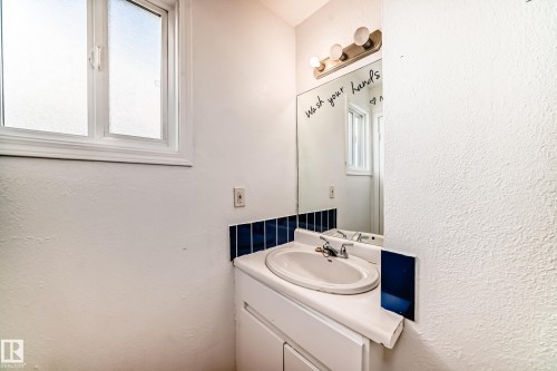 Bathroom vanity with an integrated sink, chrome faucet, and a large mirror - 8217 182 Street Nw, Edmonton, AB - Indoor Photo Showing Bathroom