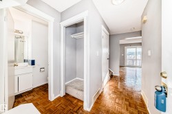 The entryway features hardwood flooring, a coat closet with carpeting, and access to a bathroom with a white vanity and mirror - 