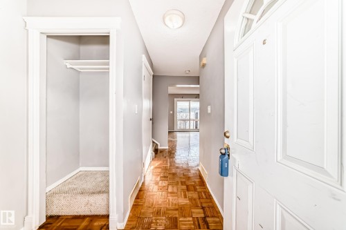 The property features a front door with an arched window, a closet with carpeted flooring and a shelf, and hardwood flooring in the hallway - 8217 182 Street Nw, Edmonton, AB - Indoor Photo Showing Other Room