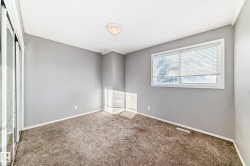 This room features carpeted flooring, light grey walls, and a window with blinds - 