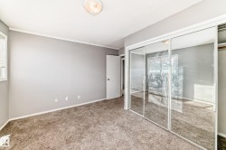 This room features mirrored closet doors, a window with blinds, and light grey walls - 