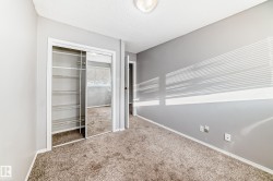 This room features carpeted flooring, light grey walls, and a closet with mirrored sliding doors and wire shelving - 