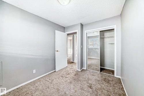 This interior room features light gray walls, a textured ceiling, and neutral-toned carpeting - 8217 182 Street Nw, Edmonton, AB - Indoor Photo Showing Other Room