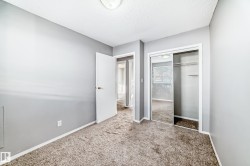 This interior room features light gray walls, a textured ceiling, and neutral-toned carpeting - 