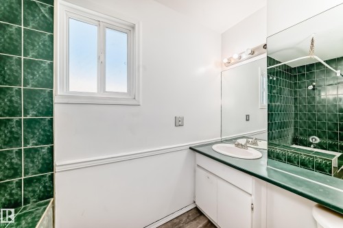 Bathroom featuring a vanity with an integrated sink, a large mirror, and a window providing natural light - 8217 182 Street Nw, Edmonton, AB - Indoor Photo Showing Bathroom