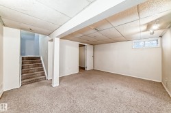Spacious room with carpeted flooring, white walls, and a window providing natural light - 