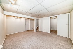 Spacious room featuring carpeting, light-colored walls, and a drop ceiling with recessed lighting - 