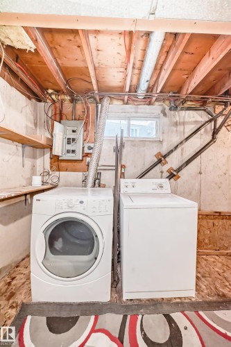 Laundry area featuring a washer and dryer, exposed ceiling joists, and a window - 8217 182 Street Nw, Edmonton, AB - Indoor Photo Showing Laundry Room