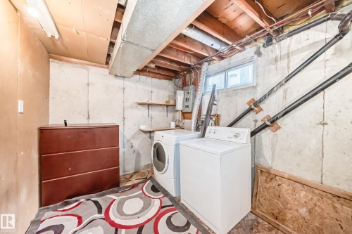 The utility area features a washing machine and dryer, exposed ceiling joists, and a window - 8217 182 Street Nw, Edmonton, AB - Indoor Photo Showing Laundry Room