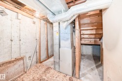 Unfinished basement space with exposed concrete walls, wooden framing, and visible ductwork - 