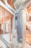 The property features a visible furnace unit, a range of ductwork, and exposed wooden framing - 
