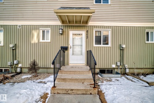 The property features a front entrance with concrete steps and black metal railings, leading to a white door with a storm door - 8217 182 Street Nw, Edmonton, AB - Outdoor