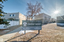 Welcome sign to Cedar West, featuring directional arrows for North and South Entrances, set against a backdrop of residential buildings - 