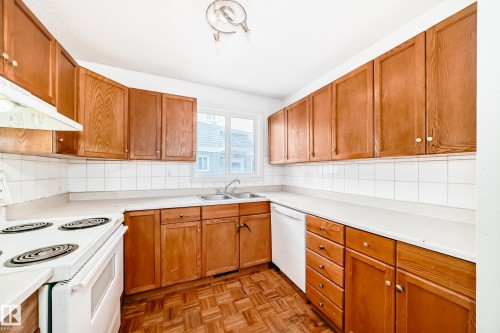 The kitchen features wood cabinetry, white countertops, and a white tiled backsplash - 8217 182 Street Nw, Edmonton, AB - Indoor Photo Showing Kitchen With Double Sink